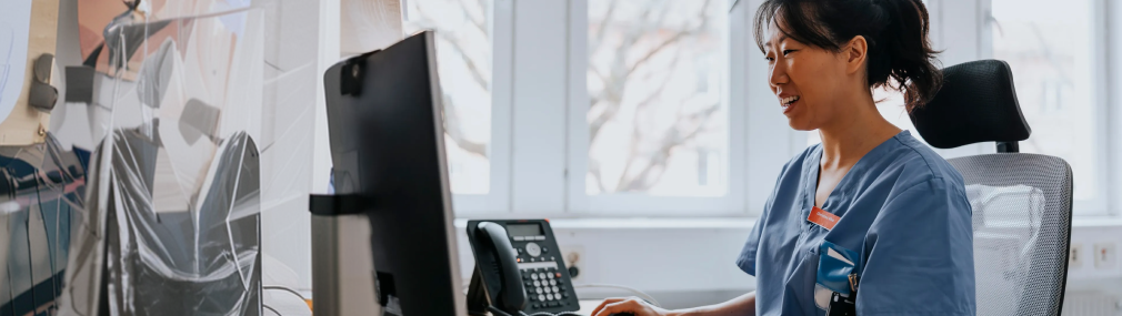 Physician using her desktop, smiling