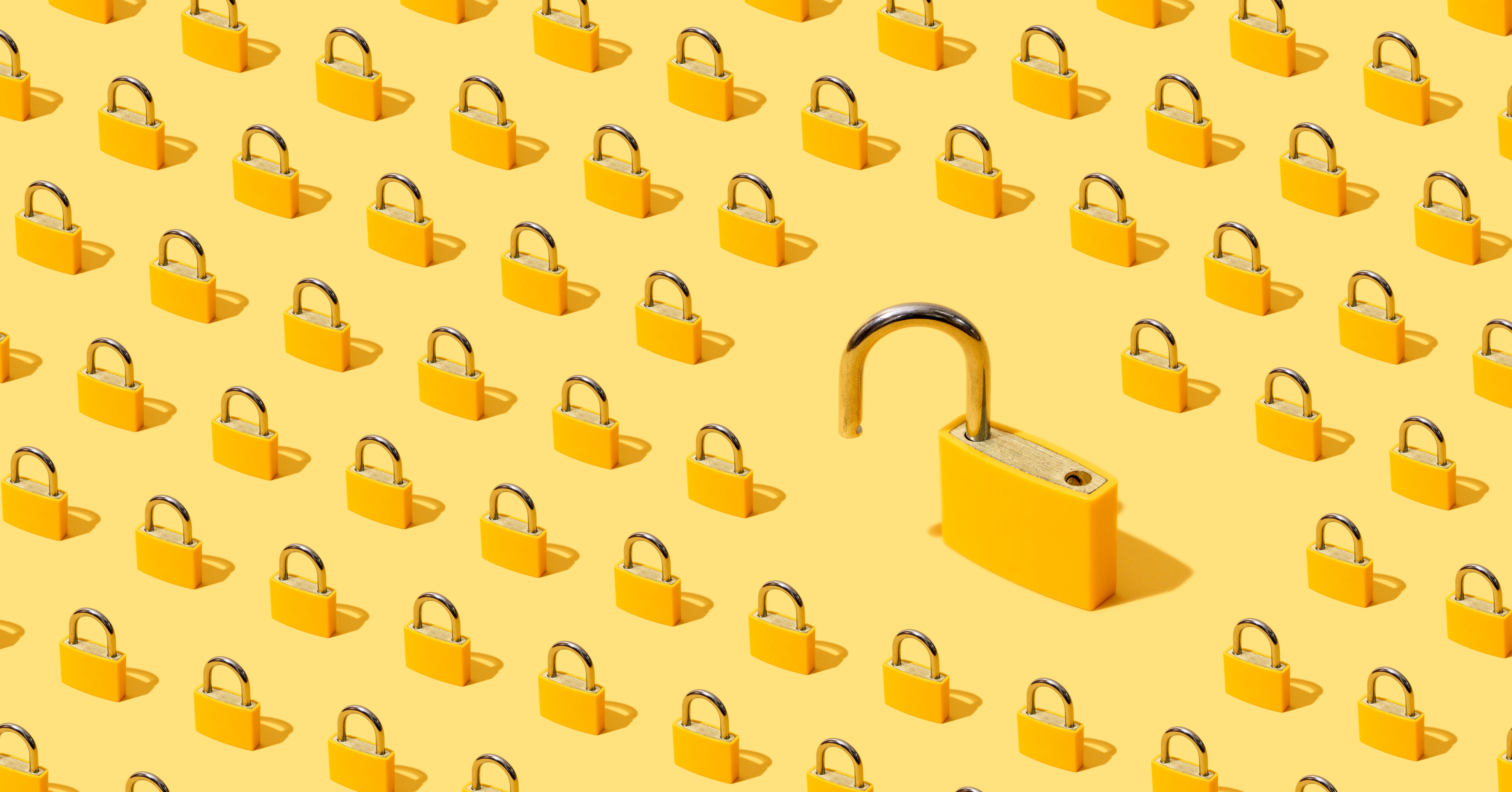 Stock image of many yellow padlocks with one open.