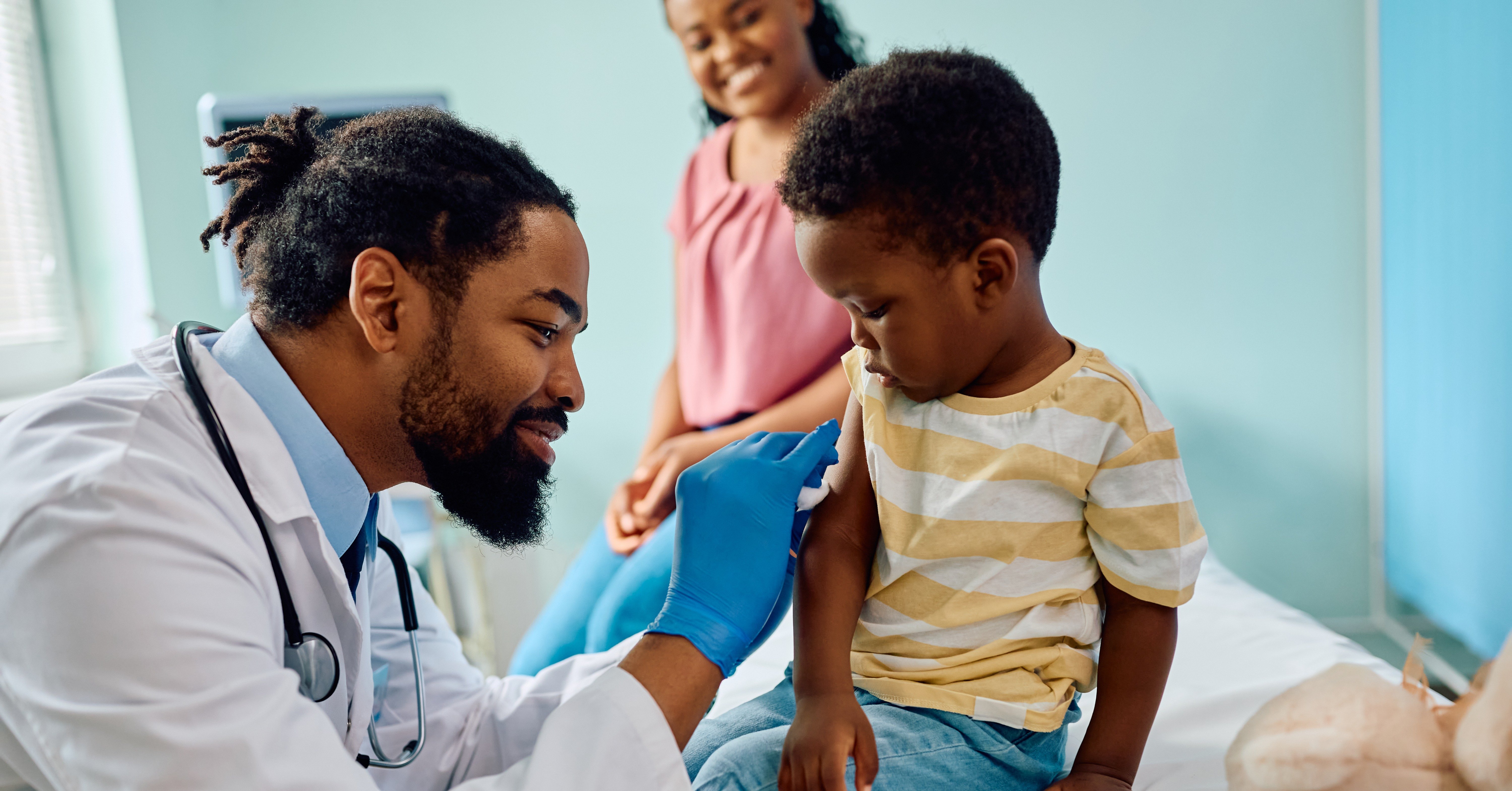 Smiling pediatrician gives a shot to a young child